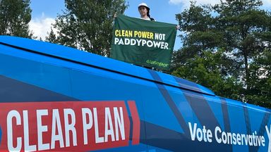 Greenpeace protester climbs on top of Conservative election campaign bus