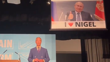 Nigel Farage speech interrupted by banner showing smirking Vladimir Putin